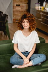 Obraz premium attractive and curly woman sitting on sofa