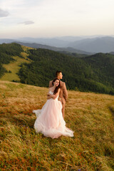 The bride and groom stand with their backs to each other against the backdrop of autumn mountains. Sunset. Wedding photography.