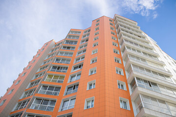 Fototapeta premium Orange multi-storey building on sky background.