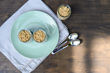Two small jars with yogurt and chia seeds, granola on a plate. Selective focus.