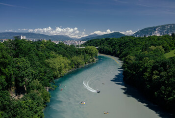 The confluence of two rivers between the banks against the background of mountains and clouds.