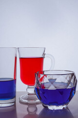 composition of different glass glasses on a white background with multicolored liquids
