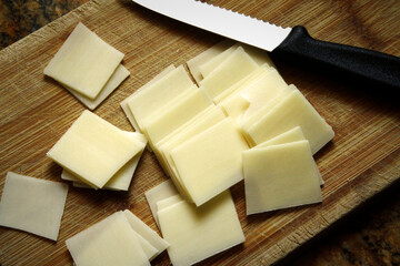 Cheddar Cheese Slices and Knife on Wood Cutting Board