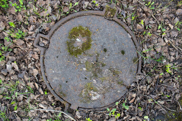 Moss-covered antique sewer manhole cover.
