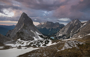 Panorama of lake Seebensee during sunset with mountain peak Sonnenspitze and Zugspitze, dramatic clouds in sky, little snow, Ehrwald Austria.