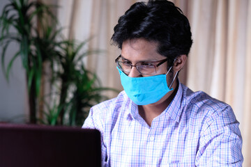 frustrated man in face mask working on laptop at office 