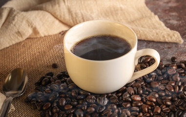 Black Coffee in White Cup and coffee beans with spoon on Old Table.
