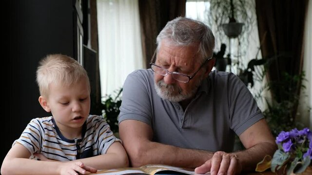 Grandfather senior man reading a book with his grandson
