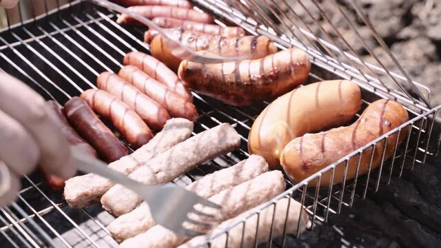 sausages and cevapcici fried meat grilled on an iron grate .