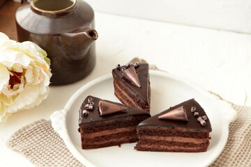 Chocolate cake slice with curl on white background. cake with whipped cream and mascarpone filling. Delicious naked cake filled with cream, topped with chocolate and decorated with flowers,