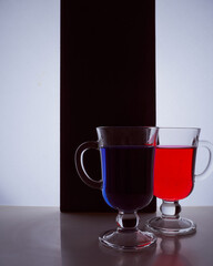 silhouettes of two glasses on a black and white background. Blue and red liquid