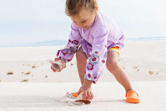4 year old girl picking up sea shells, White Sands Nat'l Monument, NM