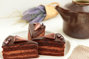 Chocolate cake slice with curl on white background. cake with whipped cream and mascarpone filling. Delicious naked cake filled with cream, topped with chocolate and decorated with flowers,