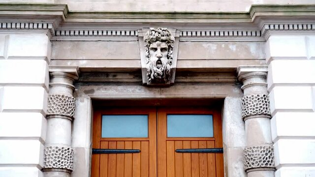 Nautical architecture with a figurehead of of ancient greek god Neptune/Poseidon above a set of wooden doors. 