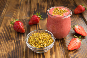 Smoothies with strawberry  and  bee pollen in the small glass jar on the brown  wooden background. Closeup.