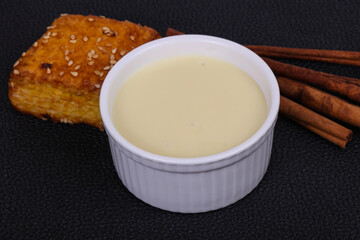 Condenced milk in the bowl with sinnamon and pastry