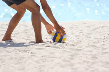 The asia man is bent pick the volleyball on sea sand have sea bokeh background in the beach at...