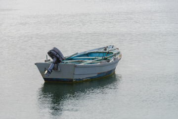 grey wooden fishing boat moored on the shore
