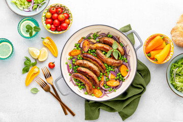 Sausages sauteed with red onions and peas, top down view