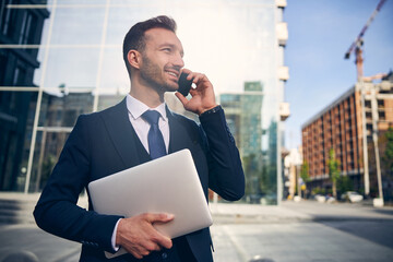 Slim brunette male talking on mobile phone outside