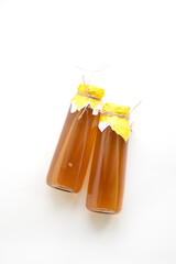Refreshing filtered kombucha tea in a glass bottle. Fermented healthy drink for two, tied with yellow paper and twine