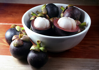 Fototapeta premium fresh purple mangosteens in white bowl, an exotic fruit for healthy living , organic mangosteens 