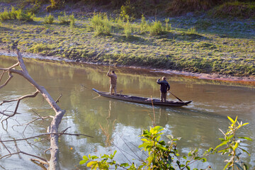Two forest guards patrolling river on the wooden canoe-shaped boat in Kaziranga National Park, Northeast, Assam, India