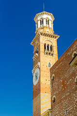 Fototapeta na wymiar Torre dei Lamberti clock tower of Palazzo della Ragione palace building in Piazza Delle Erbe square in Verona city historical centre, vertical view, blue sky background, Veneto Region, Italy