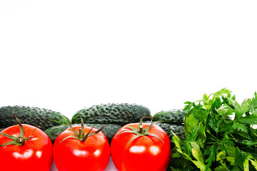 three red tomatoes, cucumbers and parsley on a white background