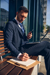 Brunette male staying outside alone and working