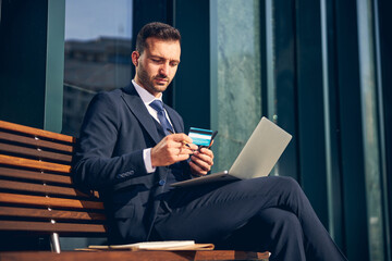 Serious businessman staying alone outside with devices