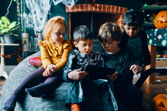 Four children sitting on a beanbag looking at a computer tablet.