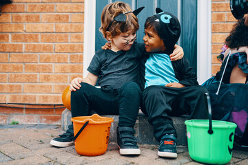 Two children dressed for Halloween with their arms around each others shoulders.