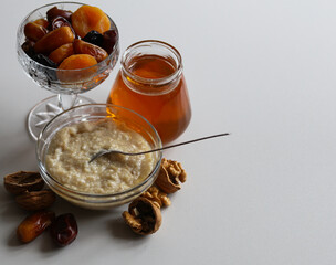 still life with oatmeal, a jar of honey, dried fruits and nuts
