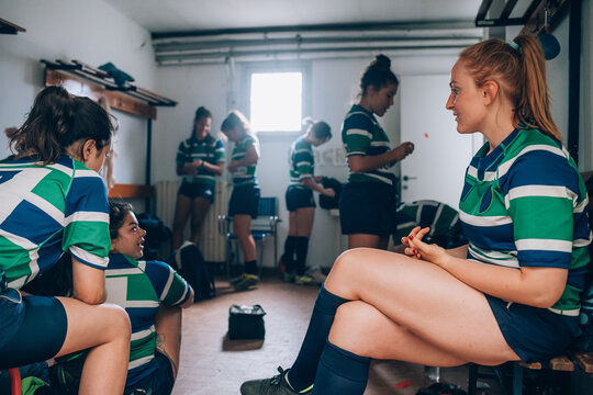 Women wearing green, blue and white rugby shirts in a changing room.