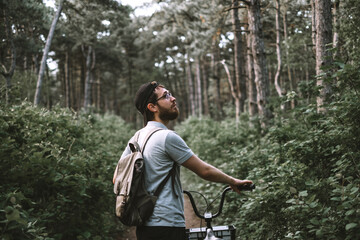 Young man with backpack cycling on a forest path, active lifestyle, playing sports in nature.