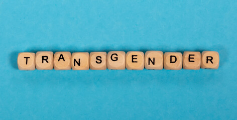 Top view of the inscription from wooden cubes TRANSGENDER on a blue background