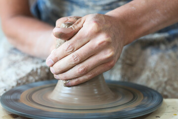 Potter hands making in clay on pottery wheel. Potter makes on the pottery wheel