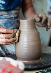 Potter hands making in clay on pottery wheel. Potter makes on the pottery wheel