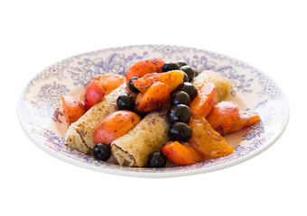 Morning breakfast with french crepes, blueberry and apricot in caramel on a plate isolated on white background. Side view.