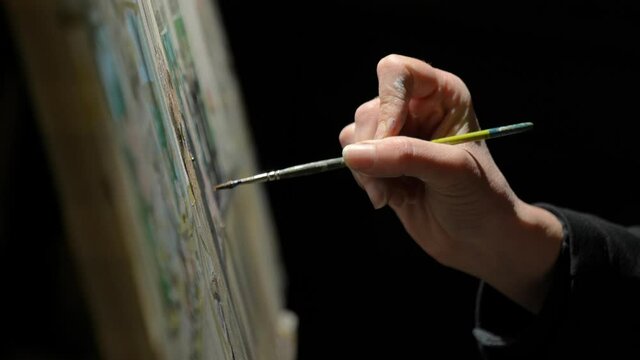 Close up hand painting on a canvas paint brush