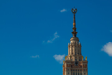 Fototapeta na wymiar The spire of the Moscow University building on a background of blue sky in light clouds