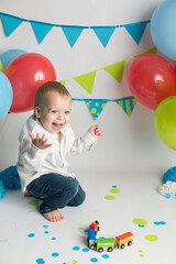 Fototapeta na wymiar portrait of a little boy. break the cake in blue. blue balloons and flags. birthday of the child