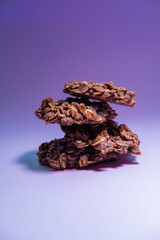 Pile of oatmeal cookies on purple background. Healthy snack. Conceptual picture. Vertical picture.