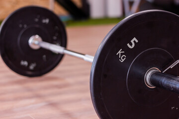Olympic gym bar with black weight disc on parquet floor