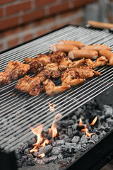 Grilled food. Grilled pork sausage, bacon and vegetables on the grill plate, top view, outdoor. Barbecue, bbq