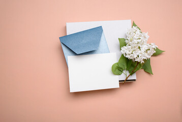 Blue envelope with white sheet for text, sprig of lilac. on a light background. Gift box.
