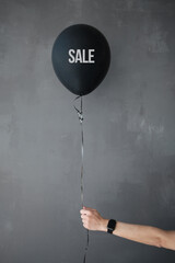 Black balloon in girl's hand. Beautiful girl with long legs. Minimalistic interior.. © Make_story Studio