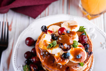Delicious homemade pancakes with banana, berries, salted caramel, mint, tea.
