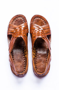 Top down view of a pair of brown leather traditional Panamanian cutarras on white background